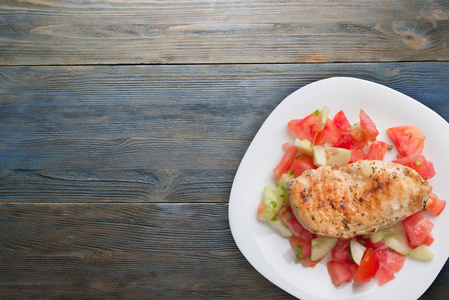 Grilled chicken breast with tomato salad, cucumbers and onions. 