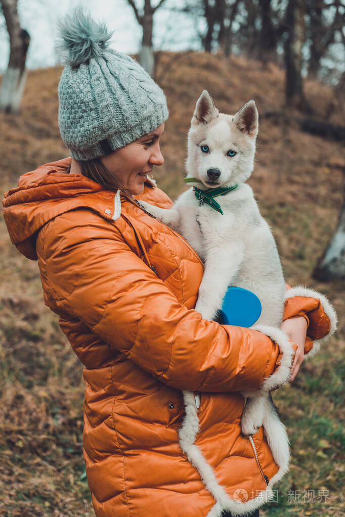 一个女人喜欢并抱着一只棕色和灰色的哈士奇小狗