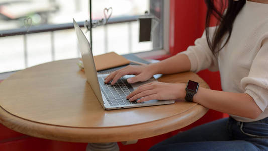 一位女大学生在笔记本电脑上打字时，在同事间工作的特写镜头