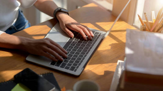 Closeup view of girl typing on laptop computer while working on