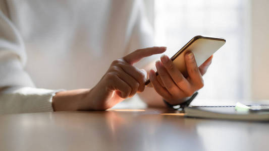 Cropped shot of girl using smartphone while working on her proje