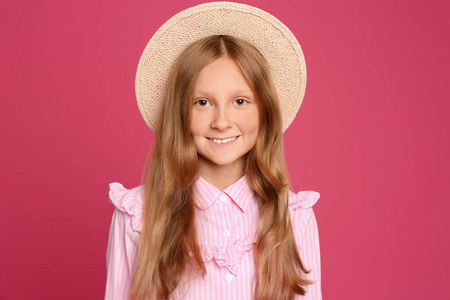 粉红色背景上戴帽子的未成年女孩肖像照片