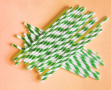 在橙色背景和复印空间的橙色背景上,饮用带有绿色条纹的吸管.