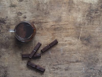 用来倒糖果的热巧克力糖衣。古老的木质背景上的巧克力块。