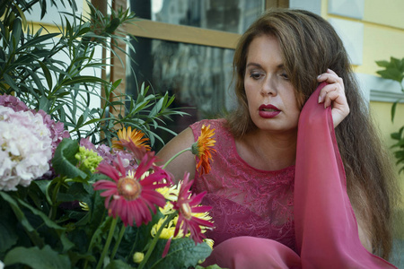 Girl in a red dress on the street among the flowers. Horizontal 