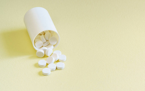 白色药丸散落在黄色背景上照片