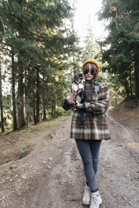 在森林里的山上，带着狗远足的女孩抱着一只小狗