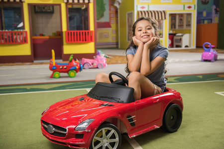 玩具车里可爱的孩子在游戏中心对着镜头微笑。
