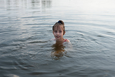 快乐美丽的小女孩在蓝色的水里游泳,露出水面微笑.