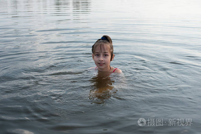 快乐美丽的小女孩在蓝色的水里游泳露出水面微笑少女喜欢温暖的天气