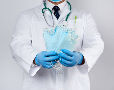 doctor in a white coat, blue latex sterile gloves holds textile 