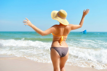 漂亮的模型后视图。海滩上穿着泳衣的女人。海上度假日