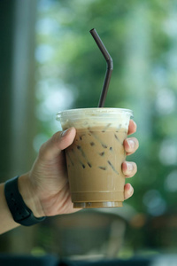 Hand holding iced latte with straw 