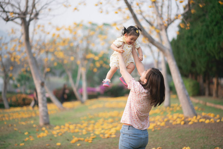 mother holding her cute baby girl in the flowers garden, Family 