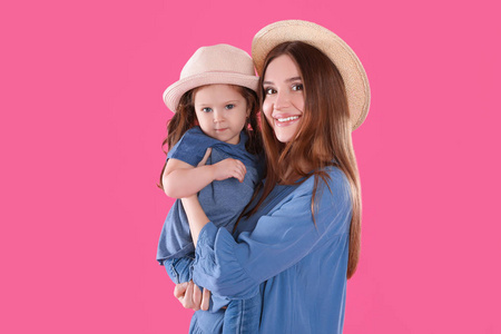 年轻的母亲和小女儿，粉红色的背景上戴着帽子