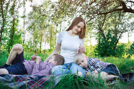 母亲和两个儿子在大自然里。和家人在公园野餐。冷静的孩子们