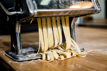 Chef rolling dough with a pasta machine. Pasta maker machine. 