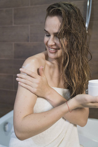 女人在浴室里用面霜涂在皮肤上。