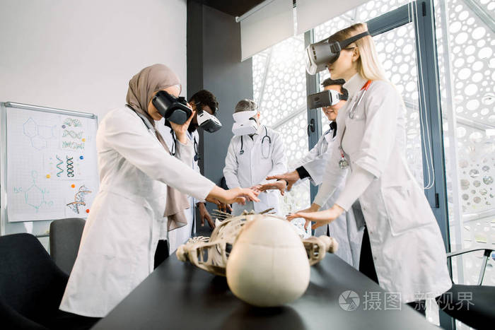 年轻的多种族研究人员在研究人体骨骼时使用虚拟现实护目镜.