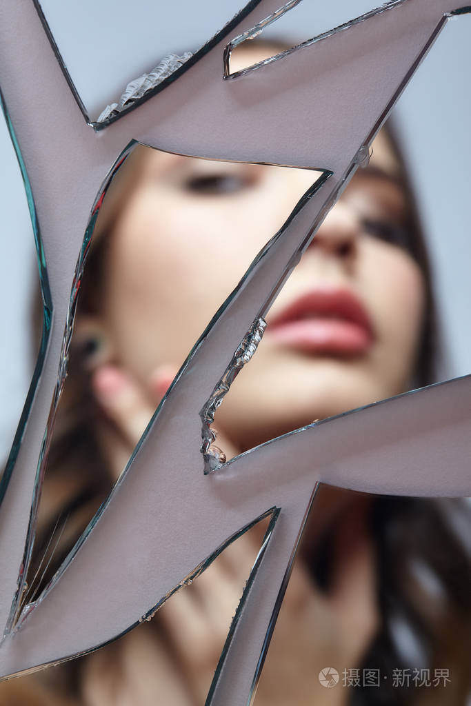 年轻女子看着破碎的镜子镜中女性的离焦画像碎片