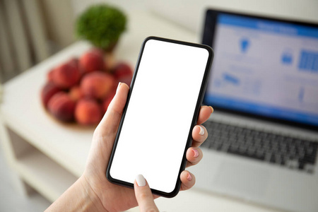 female hands holding phone with isolated screen and laptop 