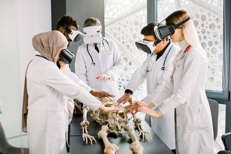 由多民族科学家组成的团队，古生物学家，遗传学在实验室工作，检查骨骼，研究人体骨骼解剖，使用虚拟现实护目镜