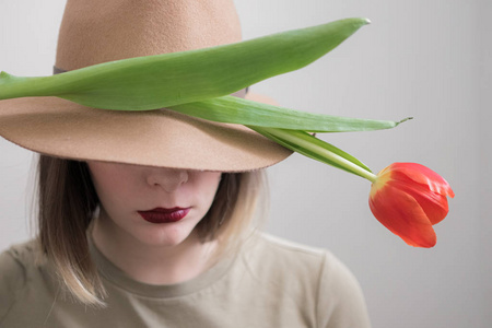 戴帽子和红唇膏的年轻女人和一个郁金香隐藏的脸
