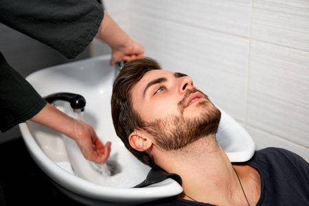 Woman applying shampoo massaging hair customer  Man wash hair in