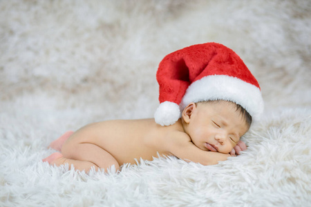 刚出生的婴儿戴着可爱的红色圣诞老人帽，睡得很安详
