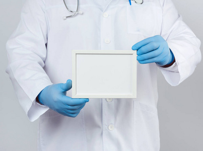 male doctor in a white medical coat and blue latex gloves holds 