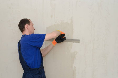 制服工人用石膏粉刷房间墙壁照片