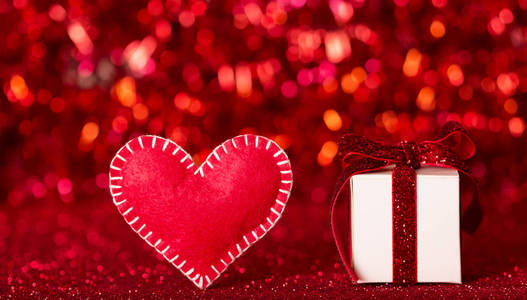 在闪闪发光的红色背景上手工制作的心形和情人节礼物