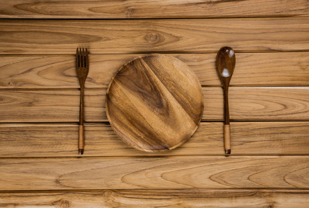 木盘子勺和叉子的特写镜头，背景是浅色的桌子