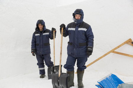 两个穿蓝色夹克去除雪的工人