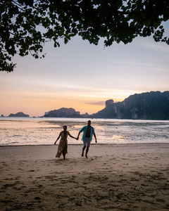 夫妇俩在泰国克拉比海滩日落时，男男女女在泰国桔梗澳楠海滩观看日落