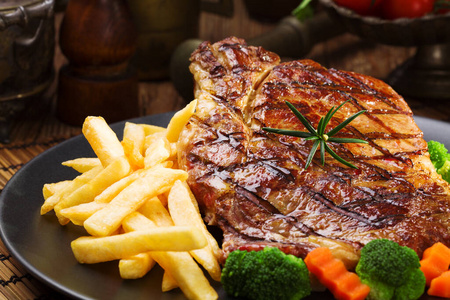 Grilled beef steak served with French fries and vegetables on a 