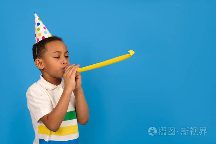 快乐的非洲裔美国男孩在蓝色背景上吹口哨庆祝生日假日和聚会的概念与