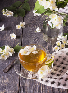 茶杯里的茉莉花茶和桌上的玻璃花瓶里的花束