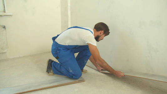 Builder in uniform puts laminate on the floor 