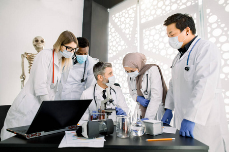 学生口罩多种族年轻的医学药剂学学生或研究人员,男主管穿着实验服和