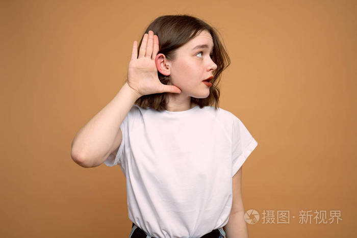 特写肖像女人把手放在耳朵附近仔细地听着橙色墙壁背景上孤立的声音