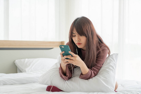 Asian women playing smartphone on bed 