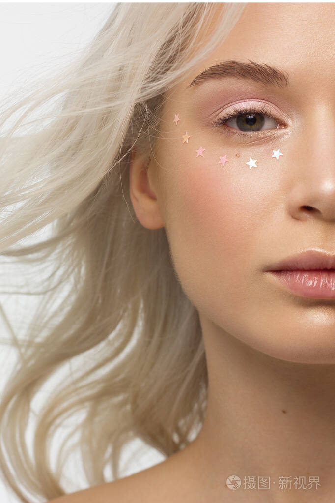 一个皮肤光洁金发卷曲的女人的半近距离肖像莱茵石的眼睛裸体化妆和