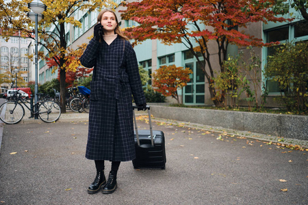 漂亮时髦的女孩在手机上聊天梦幻般地在城市街道上等出租车