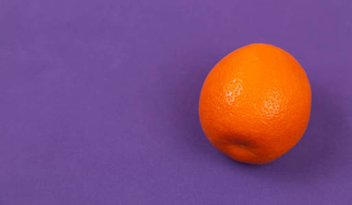 紫色纸背景上是橙色的柑橘。彩色扁钢l