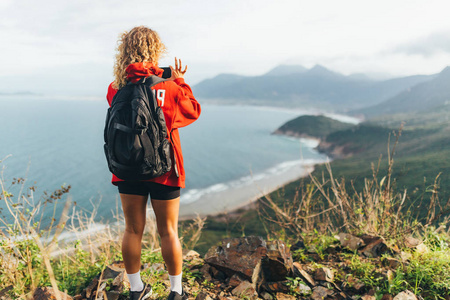 一个女孩在山顶上的后视图，在她的哈