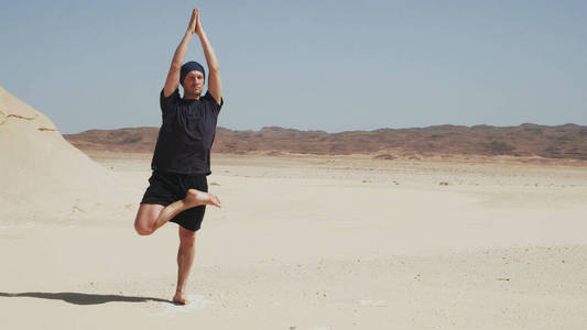一个英俊的男人在沙漠的岩石上做瑜伽