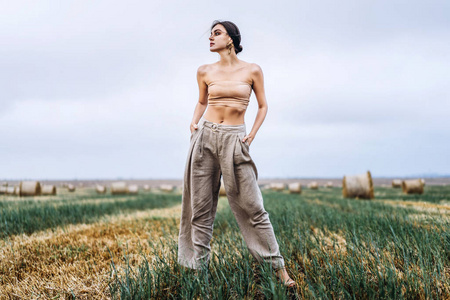 Brunette in fashionable clothes with bare shoulders standing in 