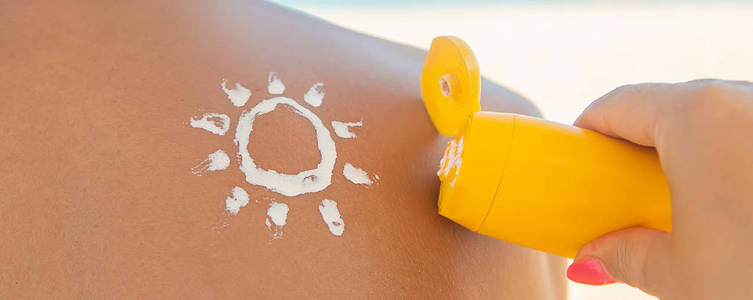 海滩上的女孩在男人的皮肤上涂防晒霜。选择性聚焦。