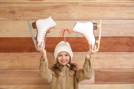 木质背景上穿着溜冰鞋的可爱小女孩